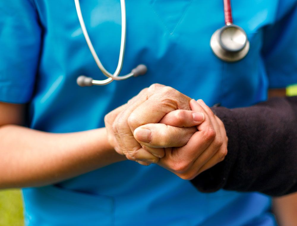 Nurse holding patient's bandaged wrist, stethoscope visible.