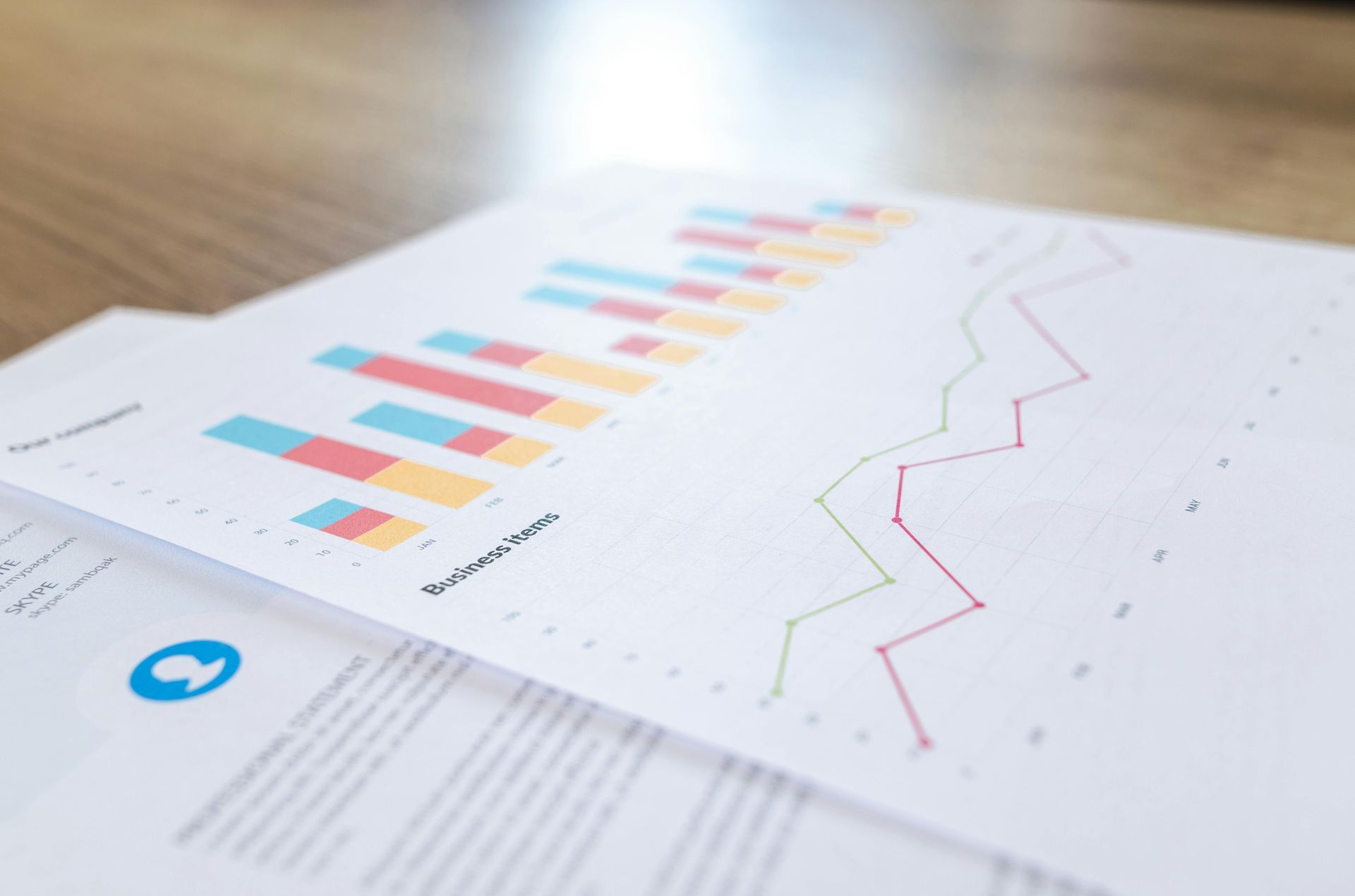Reports with bar and line graphs on a wooden desk, displaying data visualization.